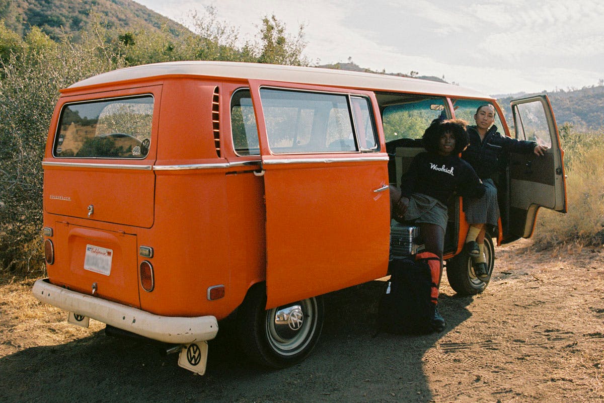 NOODLES and Alyssa Gilbert beside an orange van wearing Woolrich